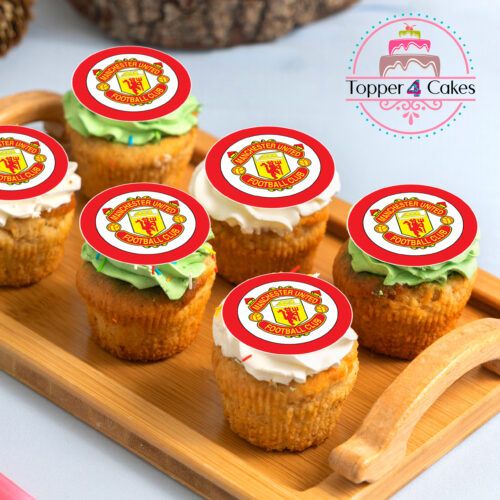 Cupcakes rest on a wooden tray, each topped with an Edible Liverpool Cupcake Topper Personalised displaying a red and yellow crest. Two cupcakes are decorated with green frosting, while the other four have white frosting. In the background, there's a Topper 4 Cakes logo featuring a pink cake design.