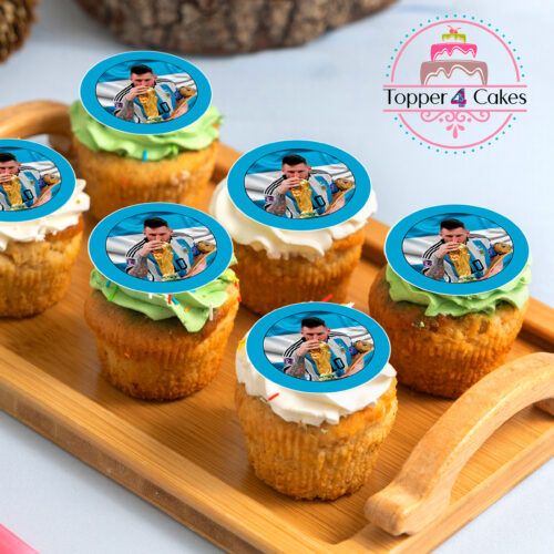 A wooden tray holds six frosted cupcakes, each decorated with an Edible Liverpool Cupcake Topper Personalised. The toppers, showcasing a person with a trophy and infused with team spirit, capture the essence of true champions. The Topper 4 Cakes logo is subtly visible in the background, completing this celebratory display.