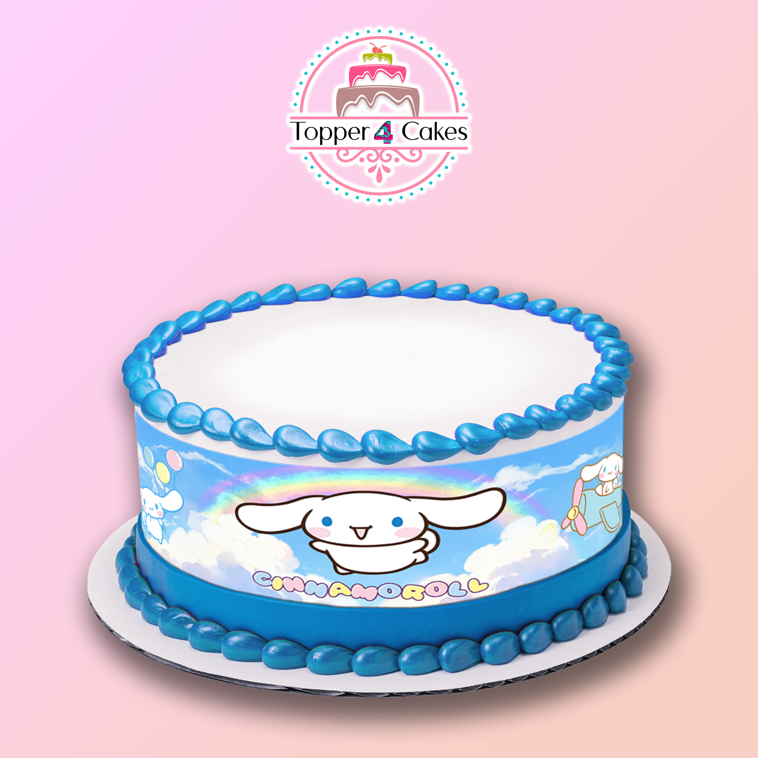 A round cake with blue icing trim, decorated with Cinnamoroll, clouds, a rainbow, and topped with the Edible Gabby's Dollhouse Ribbon (Copy). The Topper 4 Cakes logo appears above on a pink gradient background.