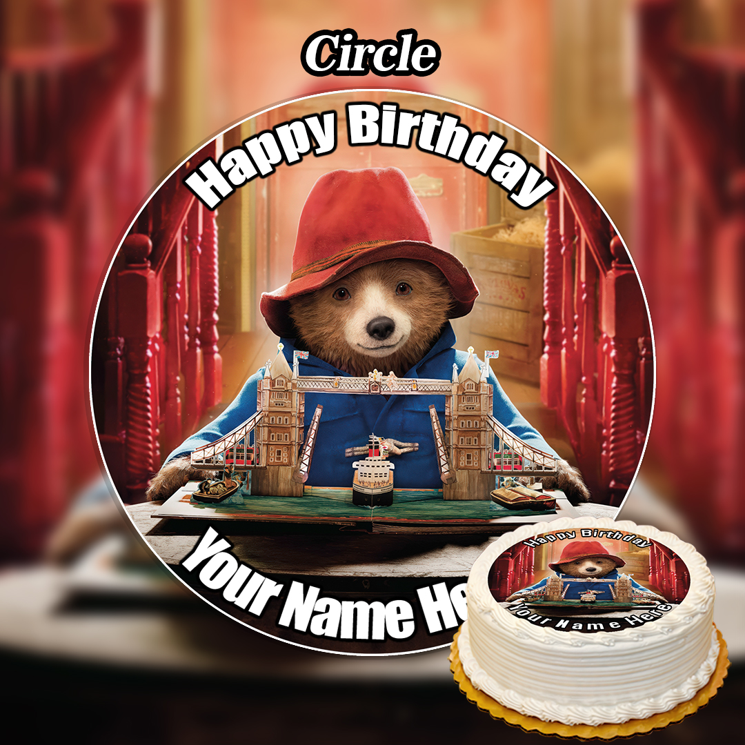 The Edible Labubu Cake Topper (Copy) is a round birthday topper featuring Paddington Bear in a red hat with Tower Bridge, "Happy Birthday" at the top, and your name at the bottom—a fun, edible alternative. Decorated cake shown nearby.